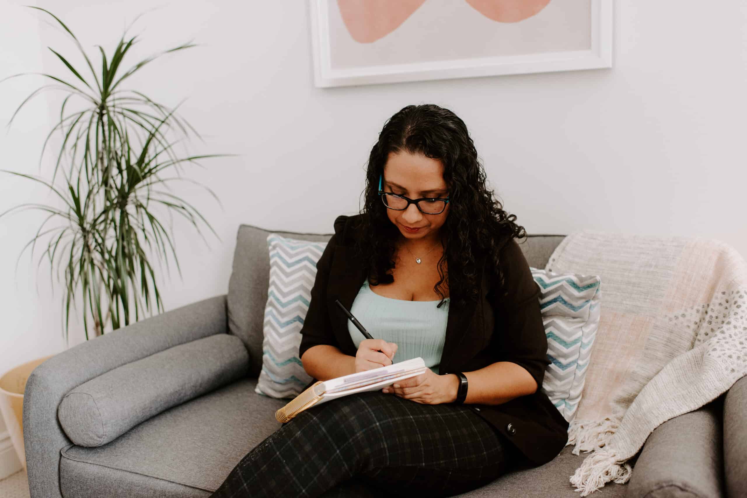 Woman taking notes on a sofa in a modern office setting.