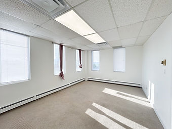 Bright empty office room with windows and sunlight streaming in.