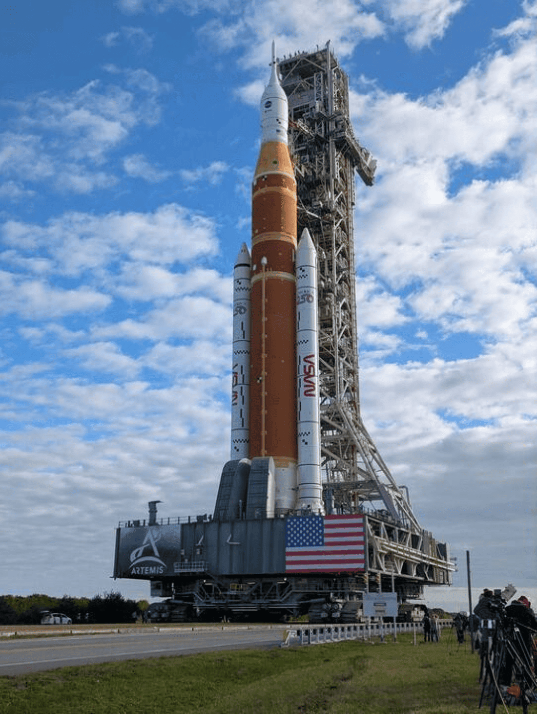NASA Artemis rocket on launch pad with blue sky and clouds.