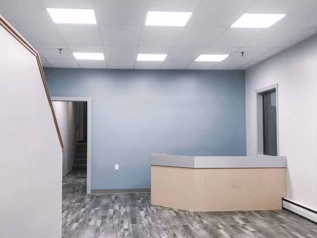 Empty office space with a light blue accent wall, wood-look flooring, and a reception desk.
