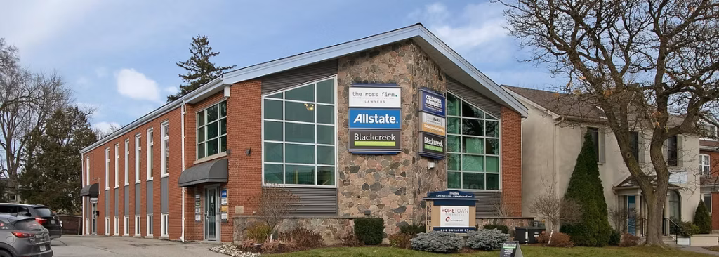 Building with "The Ross Firm," "Allstate," "Blackcreek" signs, cars parked, bare trees, blue sky.