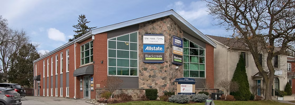 Building with "The Ross Firm," "Allstate," "Blackcreek" signs, cars parked, bare trees, blue sky.