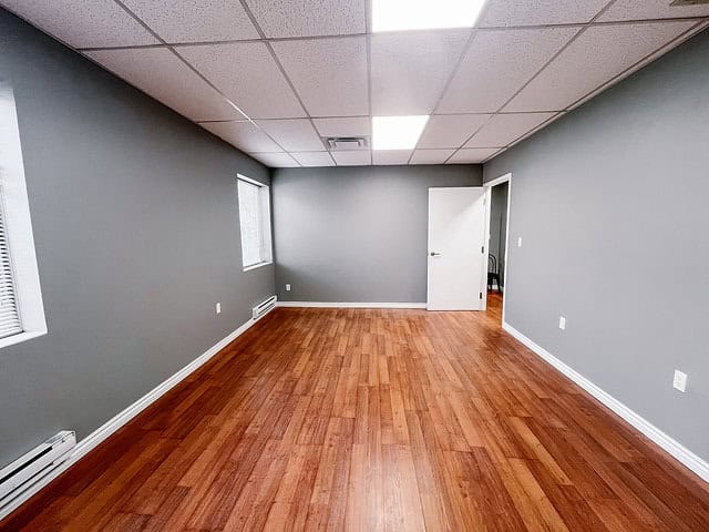 Empty office room with gray walls and wooden flooring.