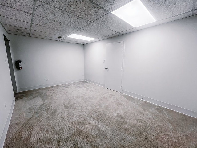 Empty office room with white walls and beige carpet in South London.