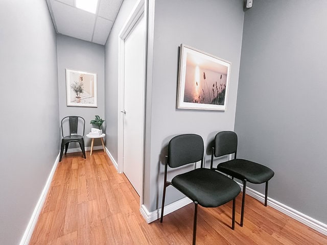 Modern office waiting area with two black chairs and artwork on the wall.