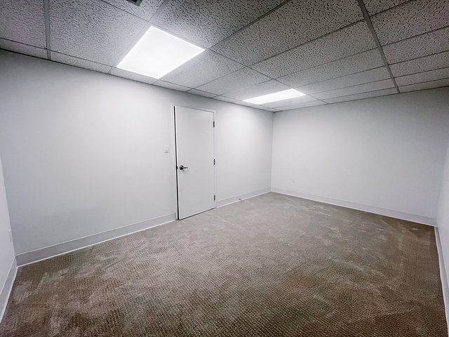 Empty office room with white walls and ceiling lights in South London.