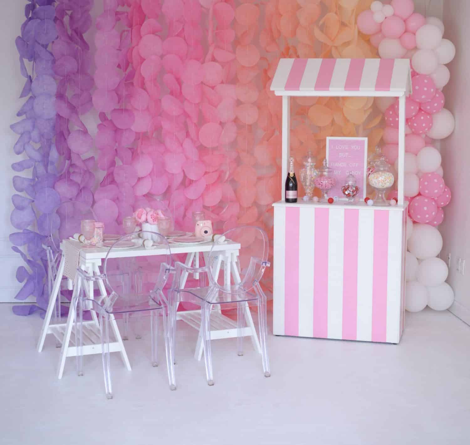 Colorful balloon wall with a small pink and white striped stand.