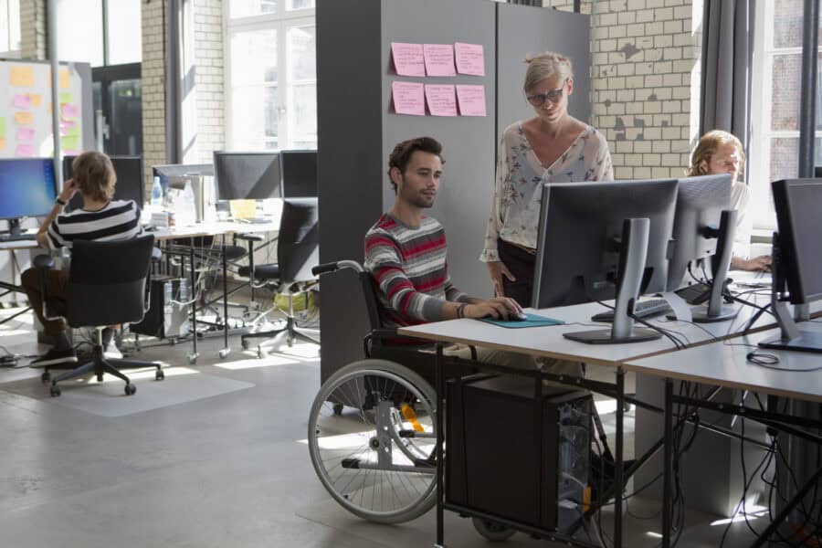 Person in wheelchair working with team in modern office environment.
