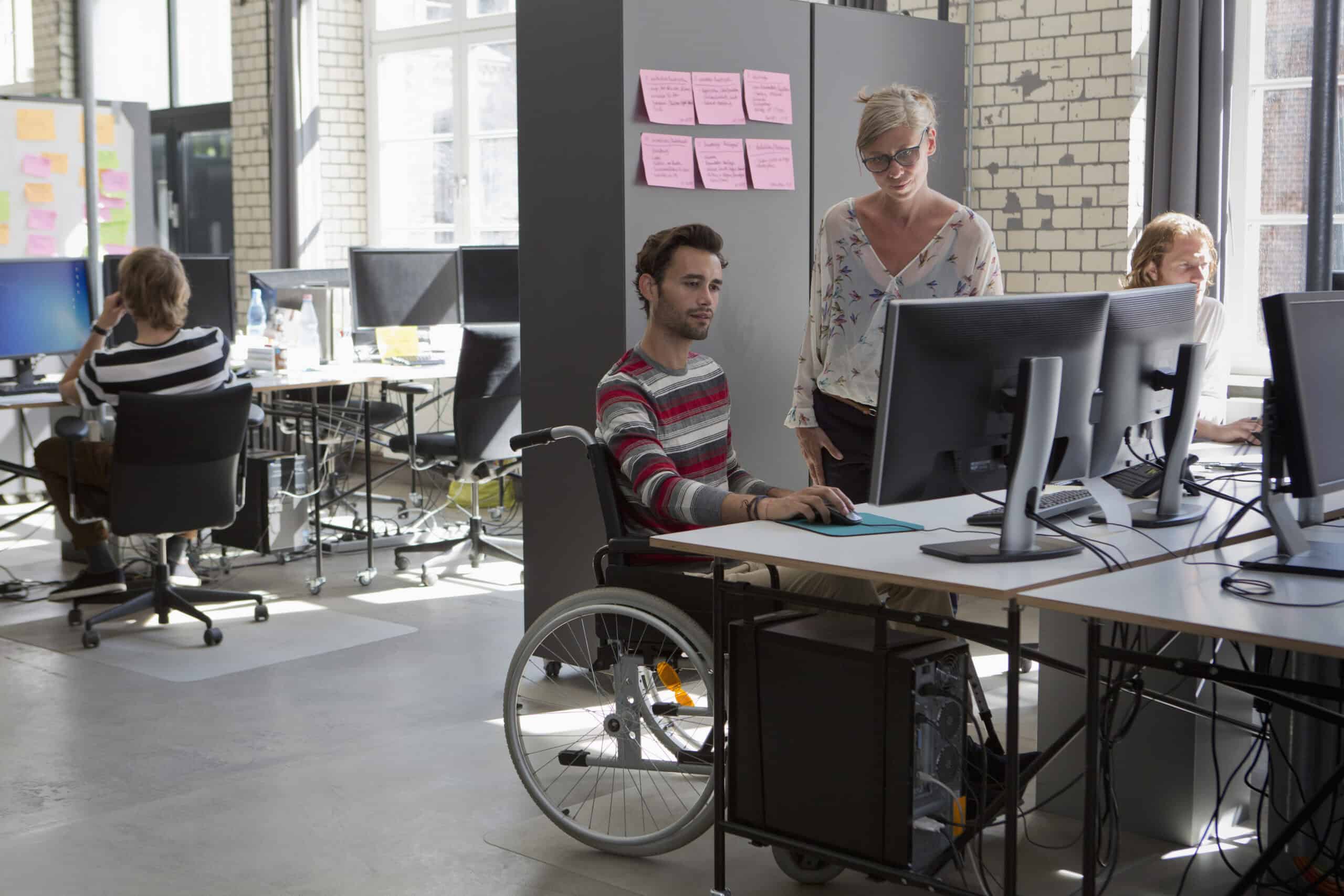 Person in wheelchair working with team in modern office environment.